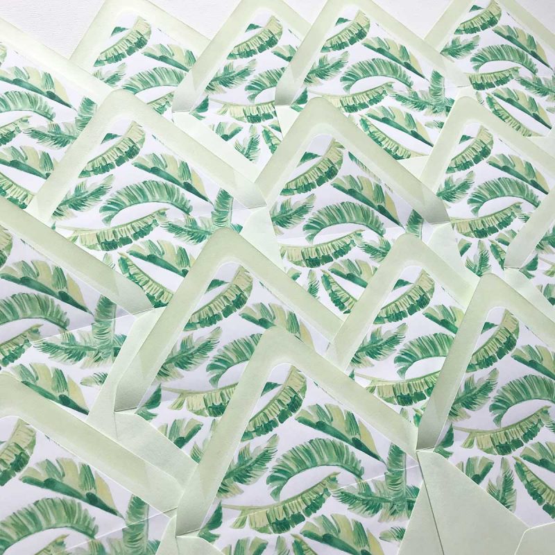 Light green envelopes lined with watercolor banana leaves by artist Michelle Mospens. Mospens Studio